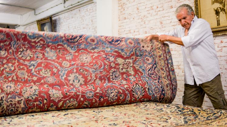 Ein Mann sortiert in einem Teppichlager in der Hamburger Speicherstadt persische Teppiche. 