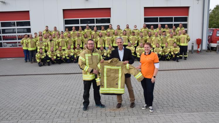 So sieht es aus, das neue Kleidungsstück der Feuerwehr: Gemeindewehrführer Dirk Schadewaldt (li.) nimmt symbolisch eine der Jacken aus den Händen von Bürgermeister Heiko Traulsen und Carolina Vehstedt von der Firma Feuerschutz Matuczak entgegen.