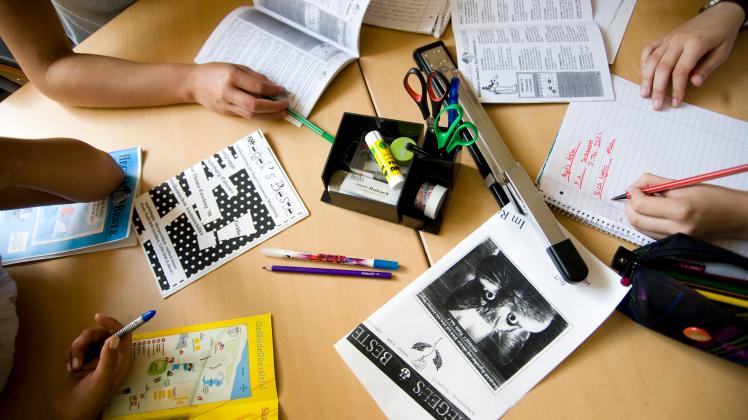 Blöcke, Stifte, Scheren und Kleber und andere Utensilien liegen während der Redaktionssitzung einer Schülerzeitung auf dem Redaktionstisch.