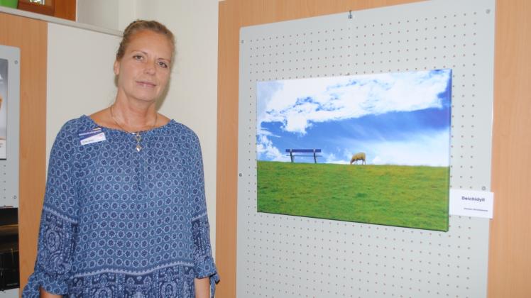 Büchereimitarbeiterin Erika Stuhr freut sich über das Bild „Deichidyll“ von Christa Christiansen.