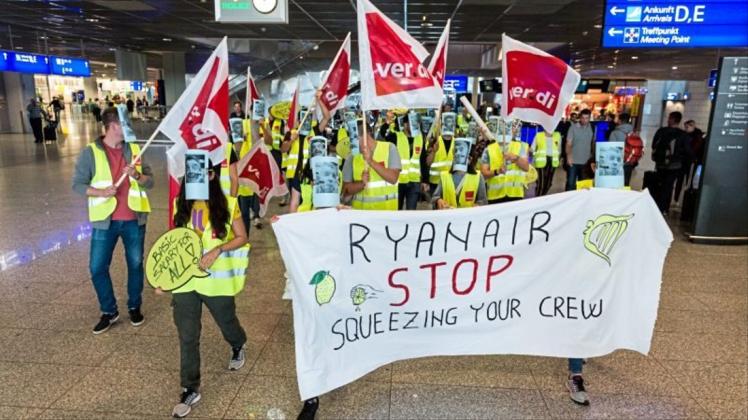 Versteckt hinter Masken und Schildern protestieren Mitarbeiter der Billigfluglinie Ryanair gegen widrige Arbeits- und Lohnbedingungen.