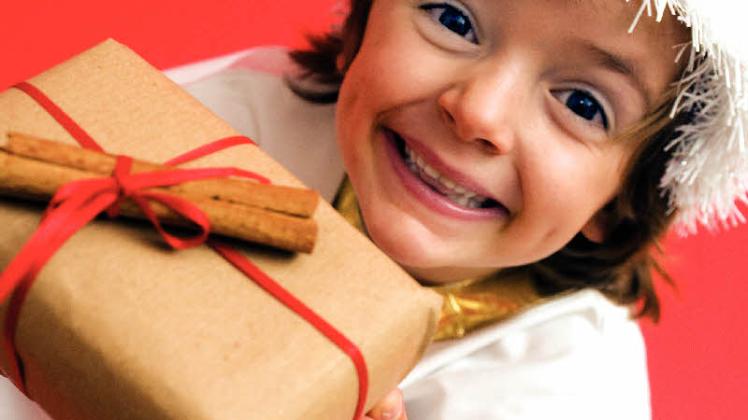 Ein kleines Mädchenfreut sich über ihr Weihnachtspäckchen.