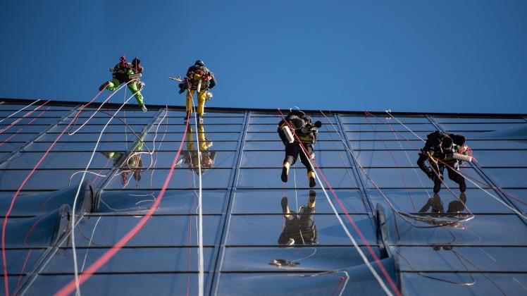 Fensterputzer klettern die Fassade der Elbphilharmonie hoch. Drei Mal im Jahr wird die Glasfassade der Elbphilharmonie von Industriekletterern gereinigt.