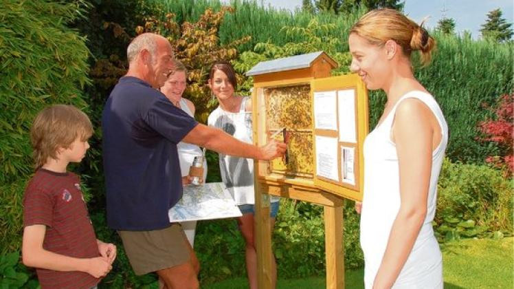 Joachim Nöhren zeigt seinen Besuchern, wie er anhand des  Bienentanzes feststellt, wo die Bienen waren.  Jannes, Inga Sievers sowie  Ann-Katrin und Bianca Bentfer schauen interessiert zu.  Foto: reimers