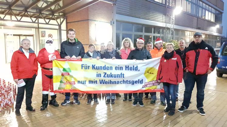 Beschäftigte der IG Bau haben am Freitag vor der Flensburger Universität ein Spalier an Weihnachtsmännern aufgestellt, um auf ihre Forderung aufmerksam zu machen. 