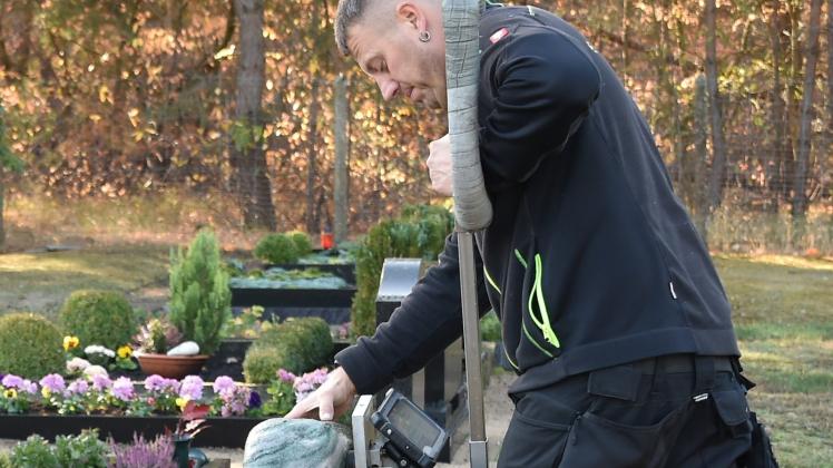 Mit einem Messgerät baut Stephan Koch Druck auf einen Grabstein auf, um die Standsicherheit zu untersuchen. 