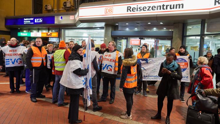 Streikende Mitglieder der Eisenbahn- und Verkehrsgewerkschaft (EVG) und Reisende vor dem Reisezentrum am Hauptbahnhof in Hamburg.
