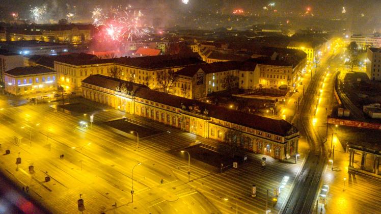 Blick vom Hotel Mercure in Potsdam auf die beleuchtete Breite Straße und das Filmmuseum während in der Silvesternacht Feuerwerk in den Nachthimmel aufsteigt. 