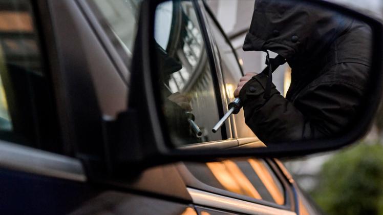 Ein Mann versucht eine Autotür mit einer Metallstange aufzubrechen (gestellte Szene). Das Landeskriminalamt in Mecklenburg-Vorpommern erwartet für 2018 erstmals weniger als 600 Kfz-Diebstähle im Land.