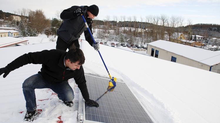 Ein Modul der Solaranlage muss vom Schnee befreit werden. Vorne schaut Axel Hübscher, der die Anlage installierte, nach dem rechten. Johann-Georg Jaeger fegt im Hintergrund.