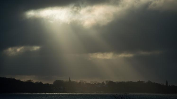 Wolken ziehen im Licht der tief stehenden Morgensonne über die Landschaft am Strelasund der Insel Rügen.