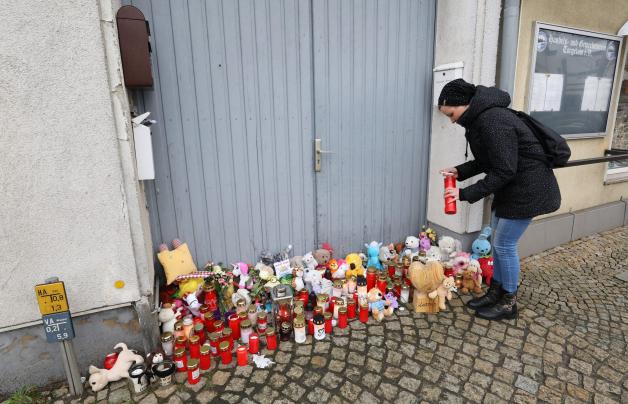 Torgelow: Eine Frau stellt vor dem Haus eine Kerze auf, wo am 12.01.2019 ein sechsjähriges Mädchen ums Leben kam.