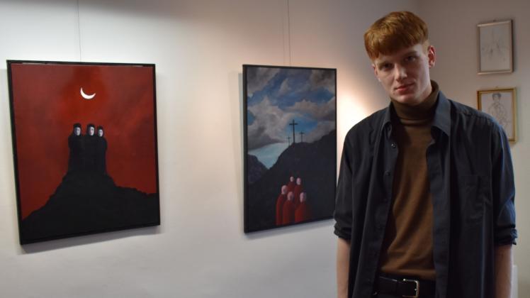 Stellt erstmals allein aus: Der 21-jährige Moritz Wittenburg lebt jetzt in Kiel und will Kunst studieren. Hier steht er vor seinen Bildern „Golgata“ (rechts) und „Finsternis („Die Sehenden)“.