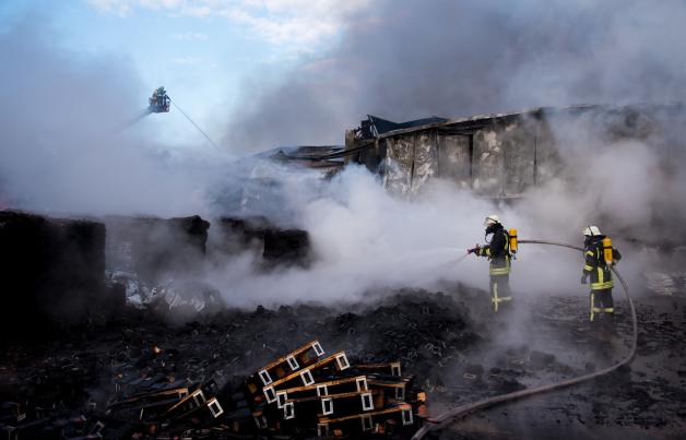 Feuerwehrleute löschen einen Großbrand in einer Torffabrik. Dort sind mehrere Lager- und Produktionshallen in Flammen aufgegangen.