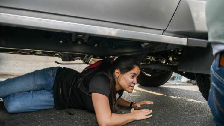 Schutz vor Kugeln sucht diese Frau unter einem Auto. Schon seit Monaten spielen sich auf den Straßen von Venezuela solche dramatischen Szenen ab.