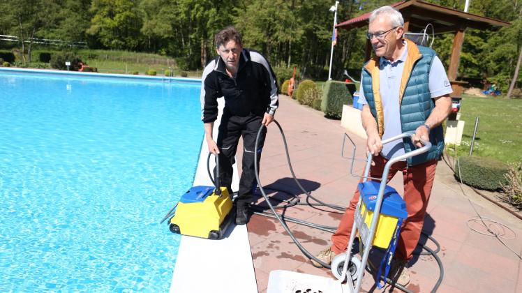 Schwimmmeister Thomas Kührmann (l.) freut sich nicht nur in diesen Tagen über jede Hilfe, hier ist Bürgermeister Ulrich Stein zu Besuch, während der Putzautomat ins Becken gesetzt wird. 