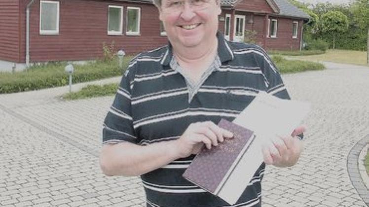 Pastor Sören Agersnap mit seinen übersetzten Liedern vor der dänischen Kirche in Süderbrarup. Foto: Kuhl