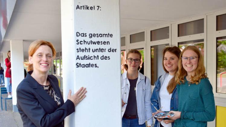 Die Säulen der Gemeinschaftsschule Brachenfeld zieren jetzt die ersten zwölf Artikel des Grundgesetzes. Bildungsministerin Karin Prien (von links) schaute sich das Werk von Lisa Zander (18), Alex Zühlke (18) und Rieke Thiel (18) an, die sich Gedanken über den Artikel 7 zum Schulwesen gemacht haben. 