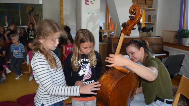 Einmal kurz berühren: (v.l.) Drittklässlerinnen Ida und Ella aus der kleinen Waldorf-Schule in Zurow schauen sich das 330 Jahre alte Instrument der Cellistin Laura van der Heijden an.