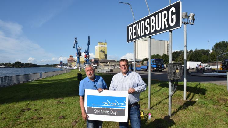 Vater und Sohn als Macher des SH Netz Cup: Wolfgang und Florian Berndt am Montag unterhalb der Eisenbahnhochbrücke. Hinter ihnen ist das Veranstaltungsgelände auf Rendsburger Boden und das Schlussstück der Ruderstrecke zu sehen.  