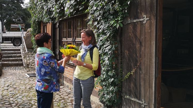 Besucherin Carmen Mehlmann (r.) bekommt Blumen von Sigrid Ulonska.