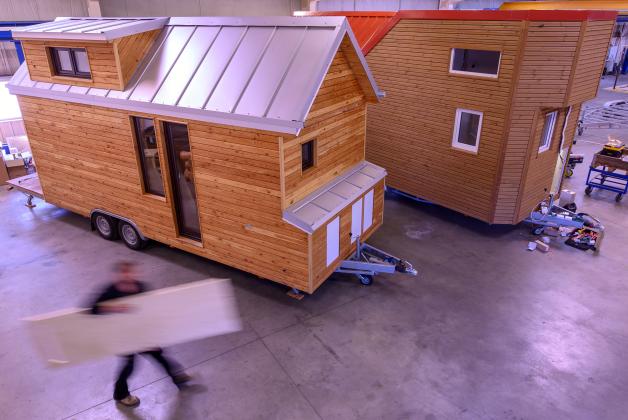 Ein Mitarbeiter trägt eine Holzplatte durch die Produktionshalle von Tiny House Wendland.