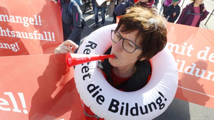 Eine Teilnehmerin der Demonstration unter dem Motto "Mehr Geld für Bildung jetzt! Für eine Zukunft für Alle!" geht mit einem Schwimmreifen mit der Aufschrift "Rettet die Bildung" durch die Rostocker Innenstadt.