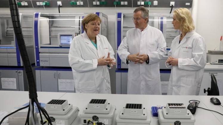 Bei ihrem Besuch der Biotech-Firma Centogene im Mai lassen sich Bundeskanzlerin Angela Merkel (l.) und Ministerpräsidentin Manuela Schwesig (r.) im Labor für DNA-Sequenzierung von Arndt Rolfs, Vorstandsvorsitzender, über die Einrichtung informieren.