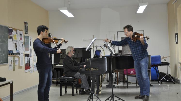 Professor Friedemann Wezel (rechts) erarbeitet mit Musikschüler Firas Alfares (links) ein Stück von Camille Saint-Saëns. Am Klavier begleitet Hendrik Wielgosz.