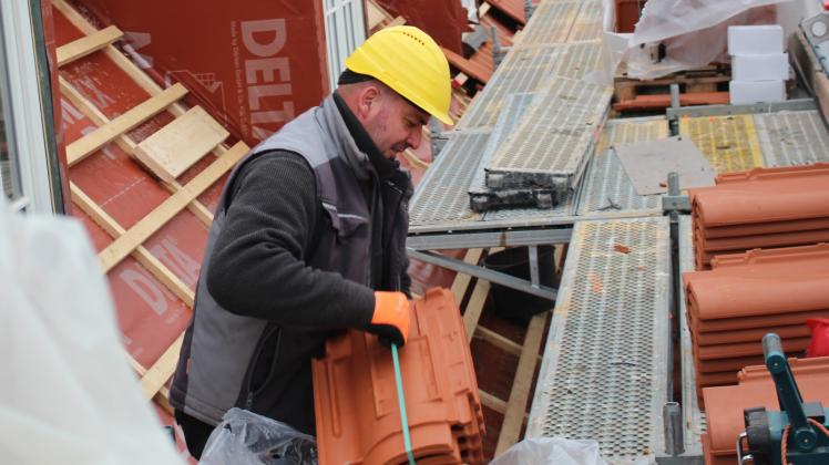 Auf 1400 Quadratmetern Dachfläche werden 12 600 Dachziegel erneuert: Dachdecker Jörg Haake bei der Arbeit mit den Dachsteinen.  