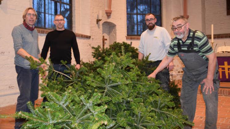 Wie aus einer Tanne ein Weihnachtsbaum wird: Bevor sie geschmückt werden kann, stellen Claus Nielsen, Christoph Kuhr sowie Christoffer und Hans-Jürgen Detlefsen (von links) den Sechs-Meter-Baum in der Kirche auf.