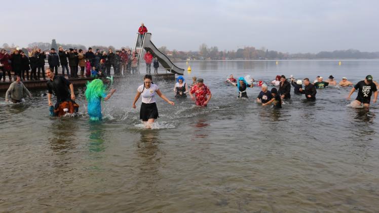 Die dick angezogenen Schaulustigen auf dem Steg und die 34 Anbader gestern Mittag im kalten Wasser des Schaalsees am Strandbad Zarrentin.  Fotos: Pohle (3) 