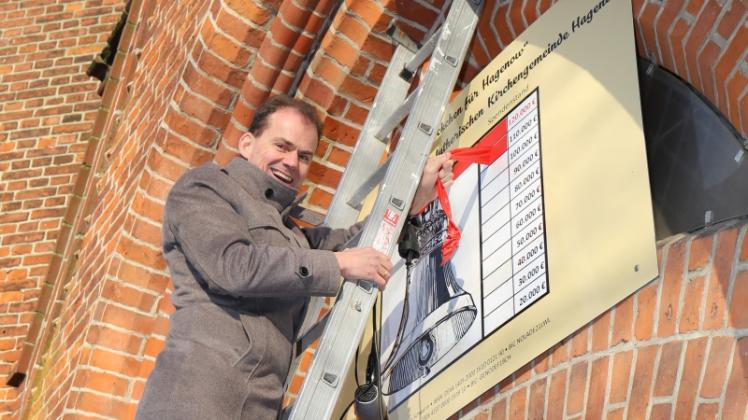 Sparkassenchef Kai Lorenzen entfernt einen der Balken am Spendenbarometer am Hagenower Kirchturm. 