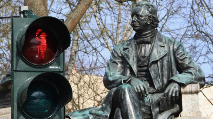 Vor dem Fontane-Denkmal am Neuruppiner Fontaneplatz steht eine Ampel mit einem Abbild des Schriftstellers 