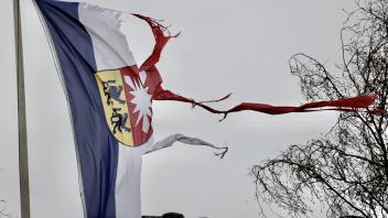 Symbolträchtig – eine vom Sturm zerfetzte Schleswig-Holstein-Fahne züngelt sich durch die Luft bei Langenhorn in Nordfriesland. 