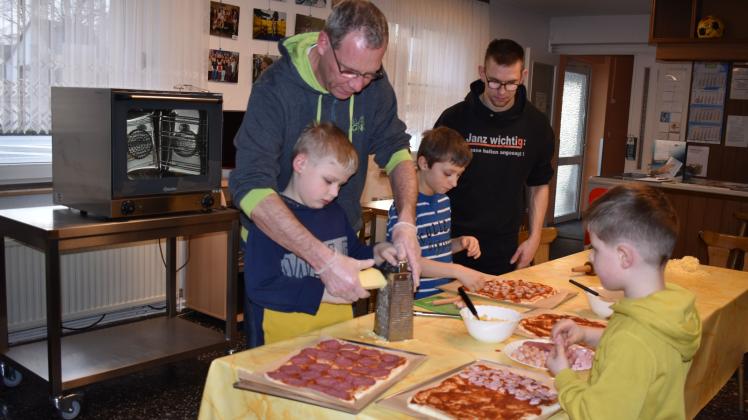 Mit vereinten Kräften wird der Käse gerieben: Clubmitarbeiter Ralf Wöhnl bereitet mit den Ferienkindern David, David und Matthias (v. l.), leckere Pizza zu. 