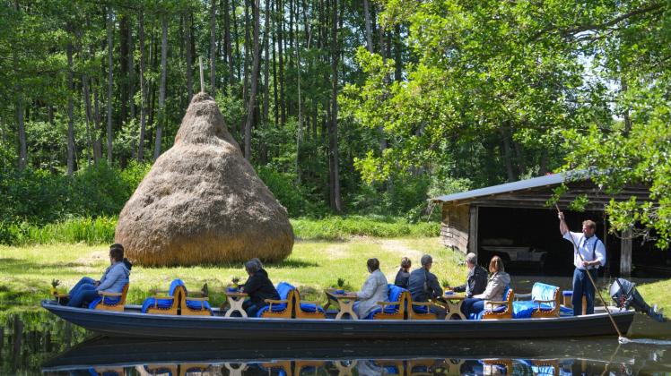 Ein Kahnfährmann steuert seinen Kahn mit Besuchern über ein Fließ im Spreewald. 