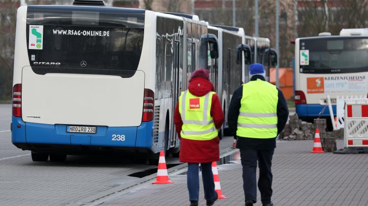 Im Busdepot der Rostocker Straßenbahn AG (RSAG) stehen Busse, Gewerkschaftsmitglieder mit Leibchen gehen über den Hof. 