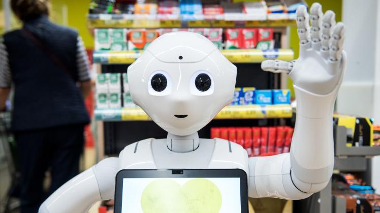 Der Roboter mit dem Namen "Pepper" steht in einem Supermarkt vor den Kassen.