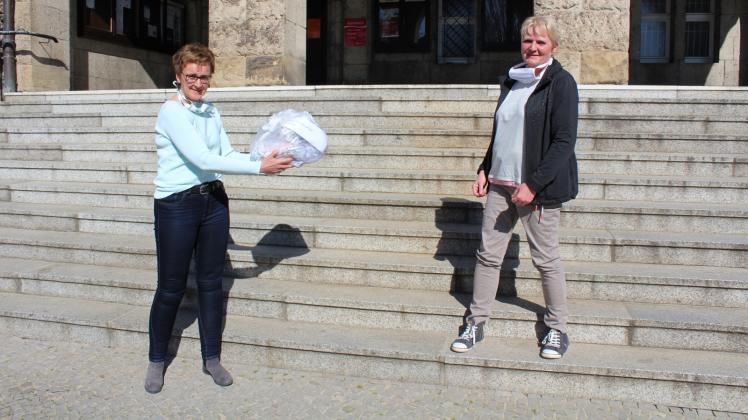 Übergabe auf Abstand: Constanze Stehr (l.), stellvertretende Bürgermeisterin von Wittenberge, übergibt selbstgenähte Mund-Nase-Masken an Liane Zucht, die einen ambulanten Pflegedienst betreibt.
