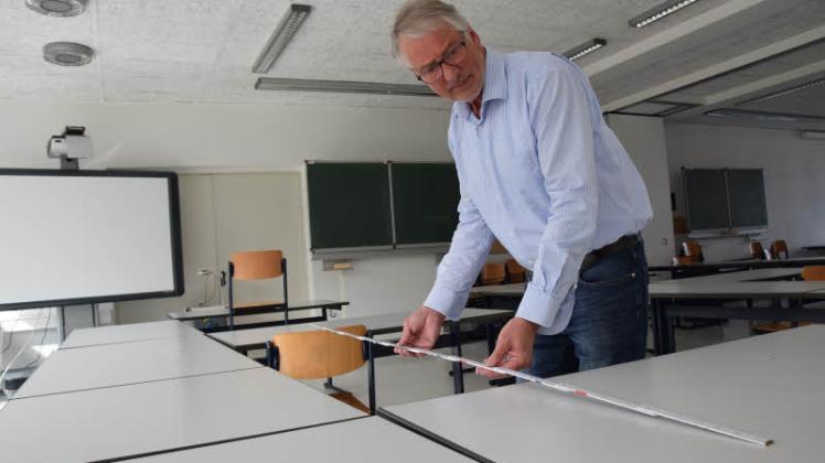 Nachgemessen: Dietmar Hilscher kontrolliert den Abstand zwischen zwei Sitzplätzen, die für die Abiprüfung vorbereitet werden.