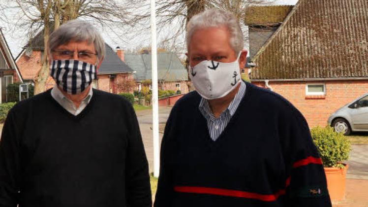 Bürgermeister Harald Klotzbücher (links) und Pastor Volker Tiedemann mit den selbst genähten Schutzmasken.