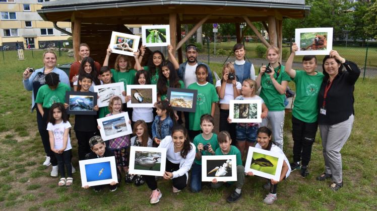Zeigen stolz ihre Fotos: Kinder und Jugendliche, die an einem Projekt in Rostock mit Ludmila Kuhlmann (r.), Manuela Matz (2.v.l. hinten) und Valentina Engler teilgenommen haben. 