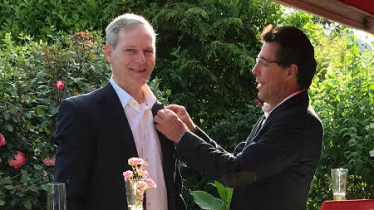 Der bisherige Präsident Walter Gyhr (rechts) heftet die Präsidentennadel an das Revers von Jürgen Heins. „