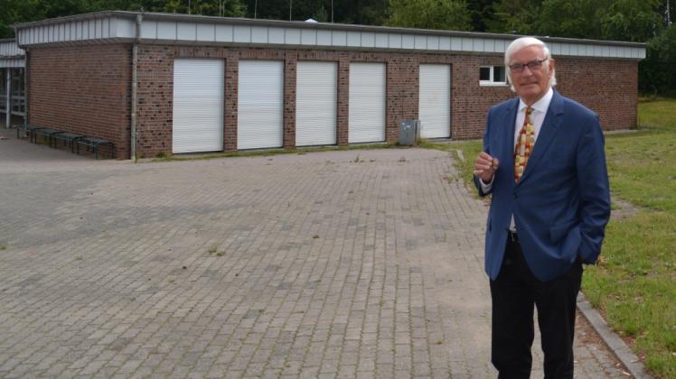 Der langjährige ehemalige Verbandsvorsteher Karl-Heinz Weinberg (CDU) bemängelt nicht nur den geplanten Abriss des neuen Klassenhauses, das auf dem Foto hinter ihm zu sehen ist, sondern auch die Rodung des idyllischen Schulwalds für einen Neubau. 