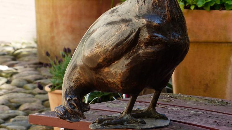 Die Skulptur stellt ein lebensgroßes, pickendes Huhn dar.