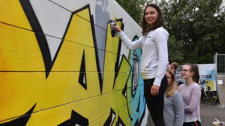 Farbenfrohe Holzwände auf dem Bolzplatz: Das Jugendparlament der Stadt Krakow am See hat die Flächen an zwei Tagen mit Graffiti versehen. Hier ist gerade die 13-jährige Paulina Krüger am Werk.