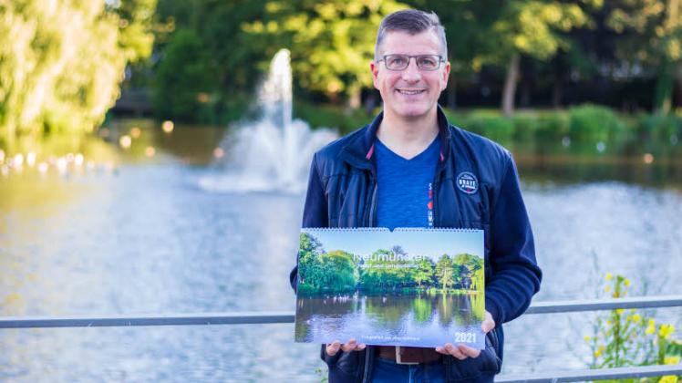 Der Gartenstädter Jörg Hoffmann präsentiert seinen Kalender vor dem Titelmotiv am Teich.