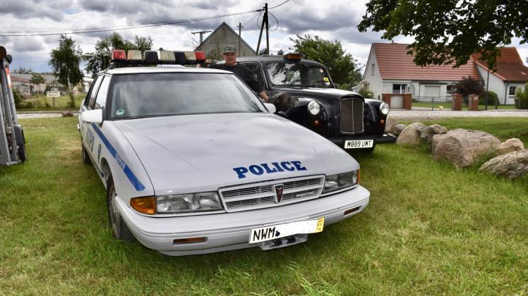 Diese Autos sind Hingucker: Axel Hamann steht in Nesow zwischen dem Polizei-Pontiac (l.) und dem London-Taxi. 