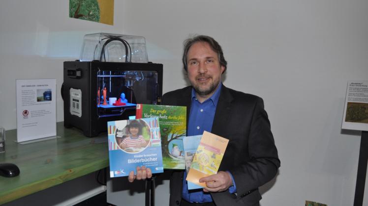 Freut sich wieder darauf, Schüler zu empfangen: Bibliotheksleiter Tilmann Wesolowski, hier mit Büchern vor dem 3D-Drucker.